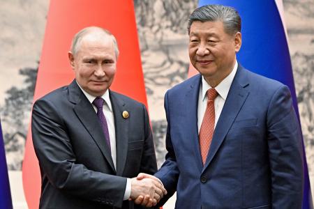 握手するロシアのプーチン大統領（左）と中国の習近平国家主席＝１６日、北京（ＡＰ＝共同）