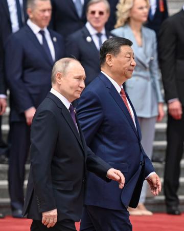 １６日、北京での歓迎式典に臨むロシアのプーチン大統領（手前左）と中国の習近平国家主席（同右）（タス＝共同）