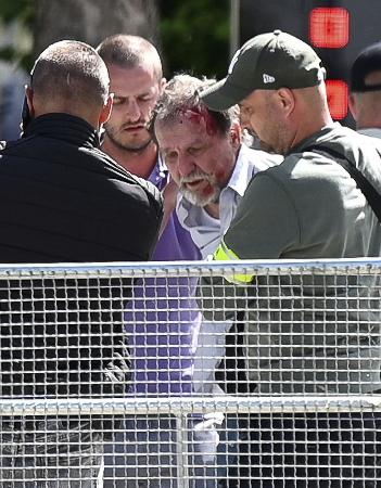 １５日、スロバキアのフィツォ首相が銃撃された中部ハンドロバで、身柄を拘束される人物（右から２人目）（ロイター＝共同）