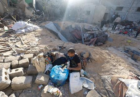 ８日、ガザ地区南部ラファで、イスラエル軍の攻撃を受けた建物の跡を調べる住民（ロイター＝共同）