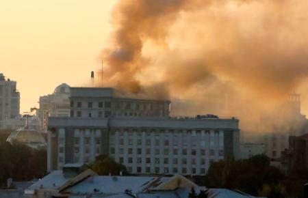 ７日、キーウ中心部の内閣の庁舎周辺から立ち上る煙（共同）