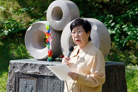慰霊碑の前であいさつする日弁連の渕上玲子会長＝７日午前、長野県大町市