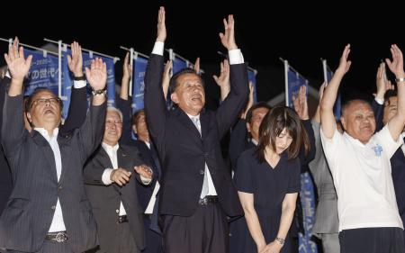 茨城県東海村長選で４選を果たし、万歳する山田修氏（中央）＝７日午後、茨城県東海村