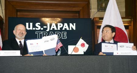 ４日、ワシントンで日米関税合意に関する文書に署名した赤沢経済再生相（右）とラトニック米商務長官。トランプ米大統領は日本から輸入する自動車への関税を引き下げる大統領令に署名した