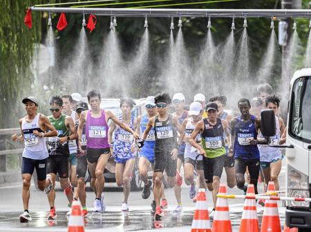 北海道マラソンで、ミストシャワーをくぐるランナー＝８月、札幌市