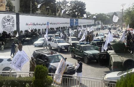 ８月、アフガニスタンの首都カブールで、タリバンの旗を掲げて復権４年を誇示する治安部隊員や支持者ら