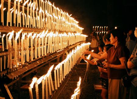 光三宝荒神社の「献灯祭」でろうそくに火をともす参拝者ら＝１３日夜、和歌山県橋本市