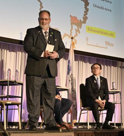 日米姉妹都市サミットに登壇した米カリフォルニア州クレセントシティーのブレイク・インスコア前市長。右は岩手県陸前高田市の佐々木拓市長＝１６日午前、大阪府泉佐野市