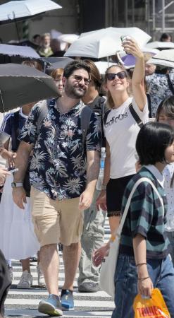 東京・渋谷駅前のスクランブル交差点を撮影しながら渡る外国人＝８月