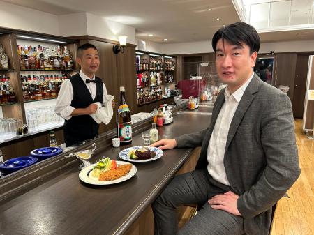 京橋モルチェの定番メニューと共に、月桂冠の日本酒「上撰」を味わう大倉泰治副社長＝東京・京橋（提供写真）
