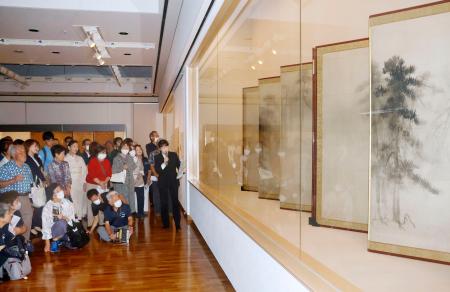 再開する石川県七尾美術館の内覧会で、学芸員から国宝「松林図屏風」の説明を聞く参加者＝１９日午後、七尾市