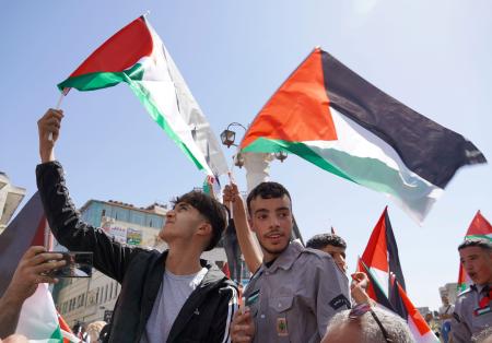 ２３日、ヨルダン川西岸ラマラで、パレスチナの旗を振って英仏などの国家承認を歓迎する若者ら。承認した国は国連加盟国の８割を超える約１６０カ国となった（共同）