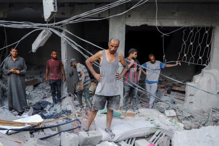 ２３日、ガザ北部ガザ市で、イスラエル軍に攻撃された住宅を調べる男性（ロイター＝共同）