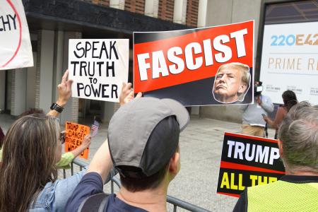 ２３日、米ニューヨークの国連本部近くで、トランプ大統領を「ファシスト」と批判するプラカードを掲げるデモの参加者（共同）