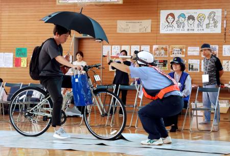 交通安全教室で、傘を差しての運転を実演する熊本県警の職員＝２５日午後、熊本県菊池市