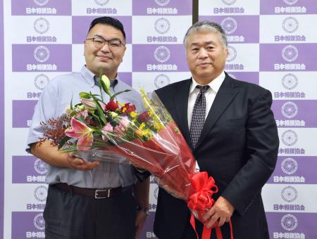 大嶽部屋を継承する熊ケ谷親方（左）から花束を受け取る大嶽親方＝２６日、両国国技館