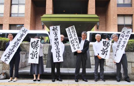 三重県４市の生活保護減額訴訟の控訴審判決後、「勝訴」などと書かれた垂れ幕を掲げる原告団の弁護士ら＝２６日午後、名古屋高裁前