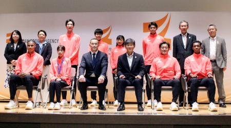 陸上の世界選手権東京大会に出場した日本代表選手らと記念写真に納まる、スポーツ庁の室伏広治長官（前列中央左）＝２６日、東京都千代田区