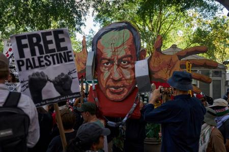 イスラエルのネタニヤフ首相の似顔絵を掲げ、抗議する人たち=26日、ニューヨーク(ロイター=共同)