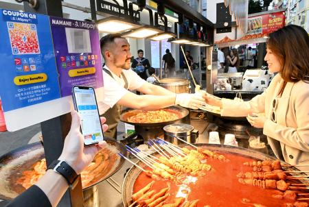 ２９日、ソウル・明洞にあるトッポッキの屋台で行われた「海外支払いモード」の実演（画像の一部を加工しています、共同）