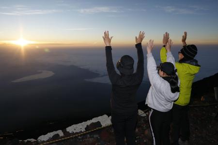 富士山の山頂で、御来光に向かって万歳する登山者＝７月