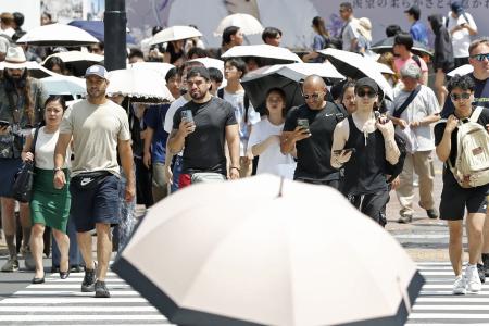 暑さの中、東京・渋谷を歩く人たち＝６月