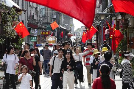 国慶節を迎え、中国国旗が掲げられた北京市内の観光地を歩く人たち=1日