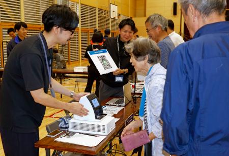 防災訓練で開設された避難所で、デジタル技術を活用したシステムに情報を登録する住民（右）ら＝５日午前、石川県珠洲市