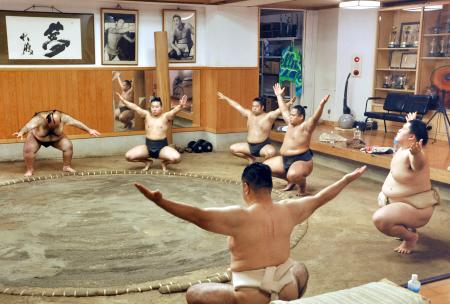 新師匠の大嶽親方（手前）の下で稽古に臨む王鵬（右端）ら。奥は元横綱大鵬の写真＝東京都江東区の大嶽部屋