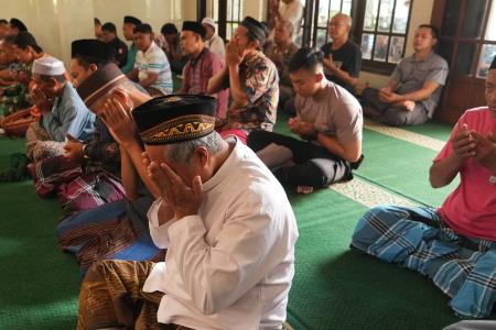 倒壊したイスラム寄宿学校の近くのモスクで祈る男性ら＝３日、インドネシア・シドアルジョ（ＡＰ＝共同）