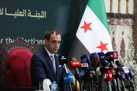 ６日、記者会見するシリア選挙管理委員会の報道官＝ダマスカス（ゲッティ＝共同）