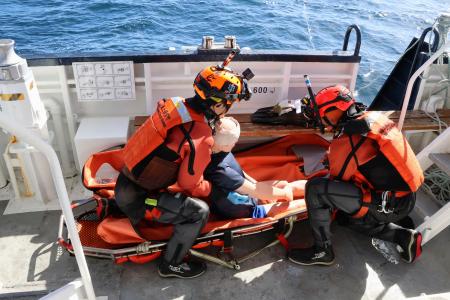 訓練で、救助対象者に見立てた人形を担架に乗せる機動救難士＝７日午前、北海道羅臼町沖