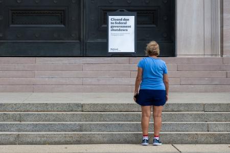米ワシントンで国立美術館の閉館を告げる掲示を見る女性=7日(ロイター=共同)
