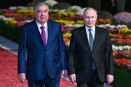 ８日、タジキスタンの首都ドゥシャンベの空港でロシアのプーチン大統領（右）を出迎えたラフモン大統領（タス＝共同）