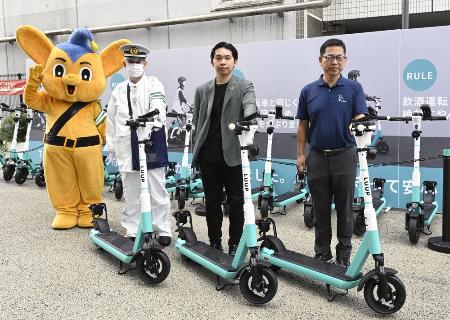 電動キックボードの講習会で写真に納まる関係者=2023年、東京都渋谷区