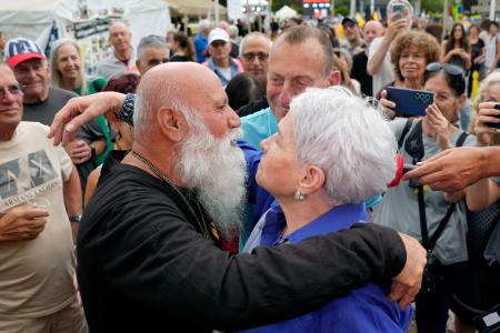 ９日、イスラエル中部テルアビブで喜ぶ、息子がハマスに拘束されたダニ・ミランさん（左）（共同）