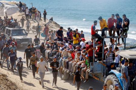 停戦を受け、避難先のガザ南部から北部に戻る人たち=10日、ガザ中部(ロイター=共同)