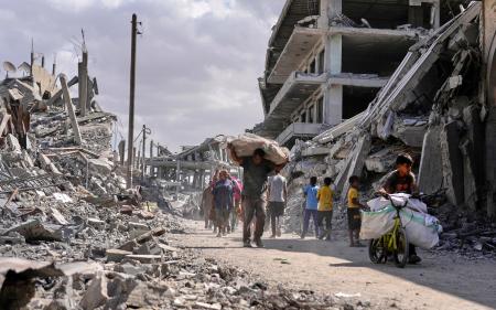 ガザ南部ハンユニスで荷物を持って歩く人たち。イスラエルとイスラム組織ハマスの停戦が発効した=10日(AP=共同)