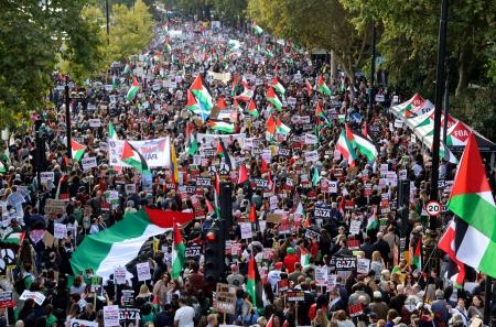 パレスチナの旗を手に行進するデモ隊=11日、ロンドン(共同)