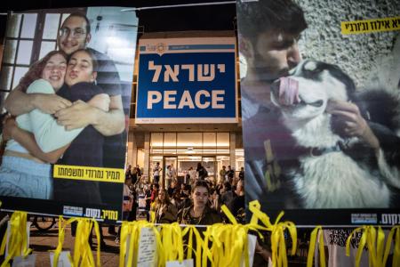 １２日、イスラエル・テルアビブの広場で、拘束中の人質の写真を見つめる女性（ゲッティ＝共同）