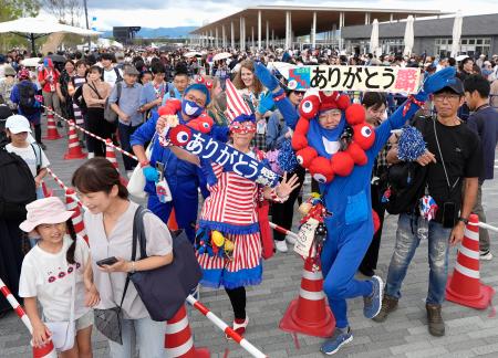 　閉幕日、ミャクミャクをイメージしたファッションで「ありがとう」などのメッセージを掲げる来場者＝１３日午前、大阪市此花区の夢洲