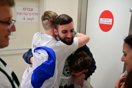 イスラム組織ハマスから解放され、抱き合うマタン・アングレストさん(中央右)=13日、イスラエル中部テルアビブ(ロイター=共同)