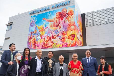 壁画の完成披露式に出席した作者のアドリー・デルロシオさん(左から3人目)とカルロス・アルベルトさん(同5人目)ら=15日午前、広島空港