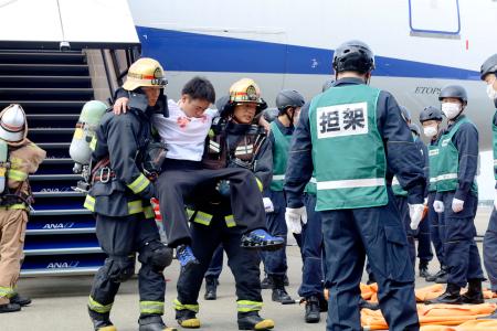 旅客機事故を想定した訓練で、機内から救出された負傷者役=16日午後、成田空港