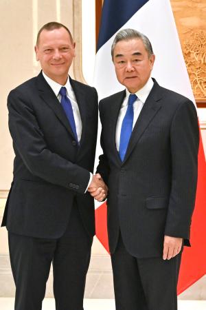 握手するフランスのボンヌ大統領外交補佐官(左)と中国の王毅外相=15日、中国浙江省杭州市(新華社=共同)