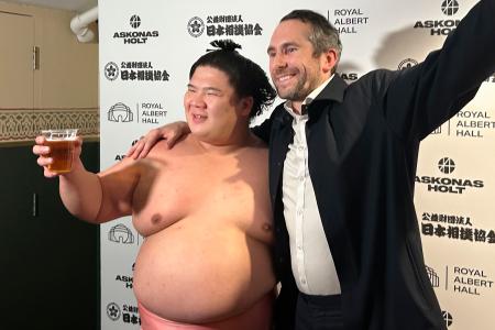 館内の従業員(右)から振る舞われたビールを手に記念撮影する宇良=ロンドン(共同)