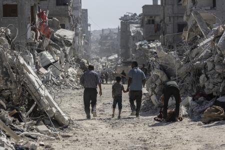 16日、イスラエル軍の攻撃で荒廃したガザ北部ガザ市で、家に戻るパレスチナ人(ゲッティ=共同)