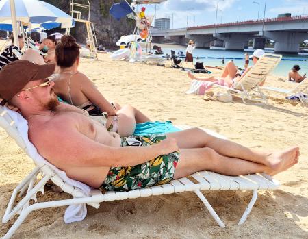 　真夏日となった那覇市の「波の上ビーチ」でくつろぐ外国人観光客ら＝１７日午後