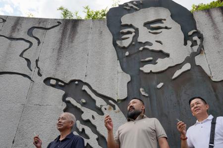 魯迅の壁画前でたばこを手に記念撮影をする人たち=9月、中国浙江省紹興市(共同)