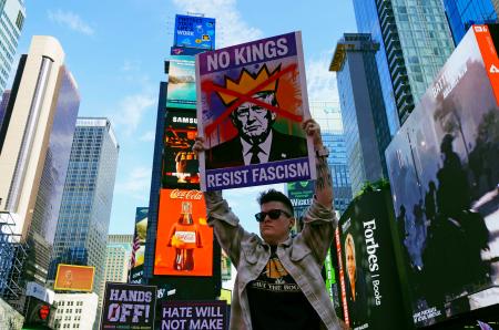 　米ニューヨークの観光名所タイムズスクエアで、「王はいらない」と書かれたプラカードを掲げるデモ参加者＝１８日（共同）